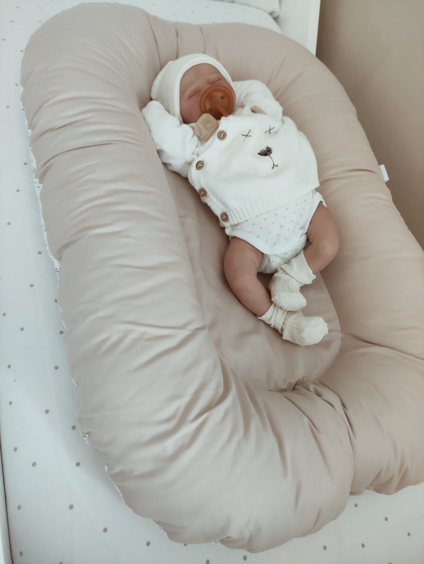 Cuna reductor de nido en colores suaves, ideal para proporcionar un entorno seguro y confortable al bebé.